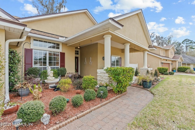 view of front of property with a garage, stone siding, a front lawn, and stucco siding