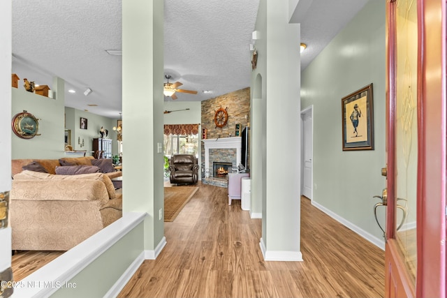 foyer entrance with ceiling fan, a fireplace, a textured ceiling, and wood finished floors