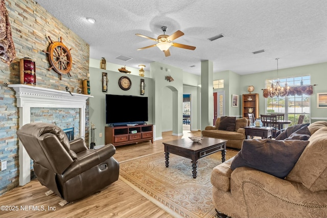 living room with a fireplace, visible vents, arched walkways, and wood finished floors