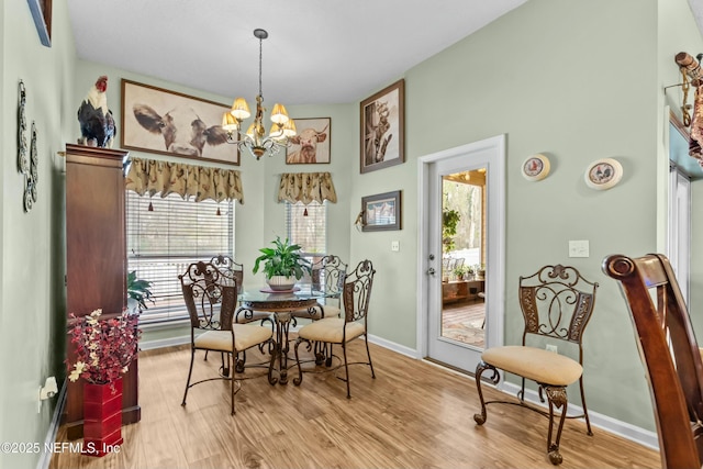 dining area with a chandelier, light wood finished floors, and baseboards