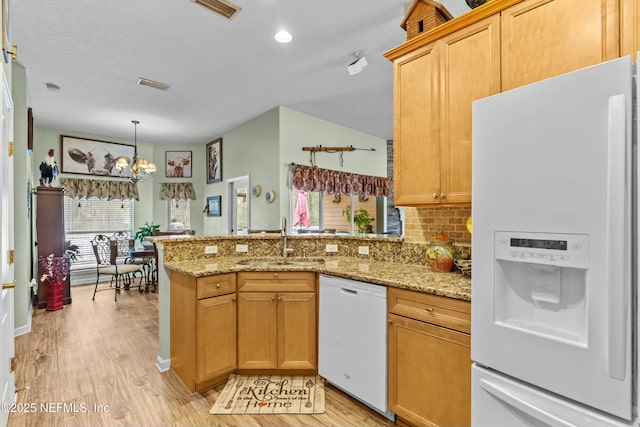 kitchen with white appliances, visible vents, decorative backsplash, a peninsula, and a sink