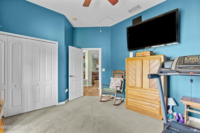 interior space featuring a textured ceiling, ceiling fan, carpet floors, visible vents, and a closet