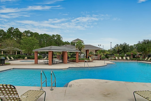 pool with a patio, a hot tub, and a gazebo