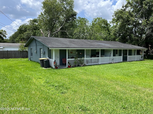 view of front of house with a porch, roof with shingles, a front yard, and fence