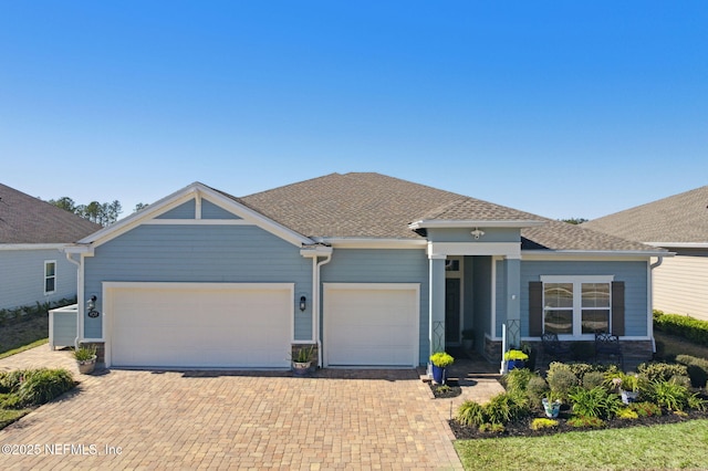 view of front of house with a garage, a shingled roof, and decorative driveway