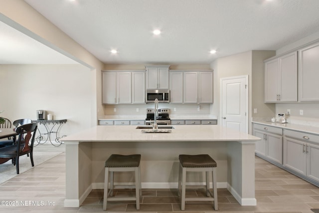 kitchen featuring stainless steel appliances, a center island with sink, a sink, and a breakfast bar area