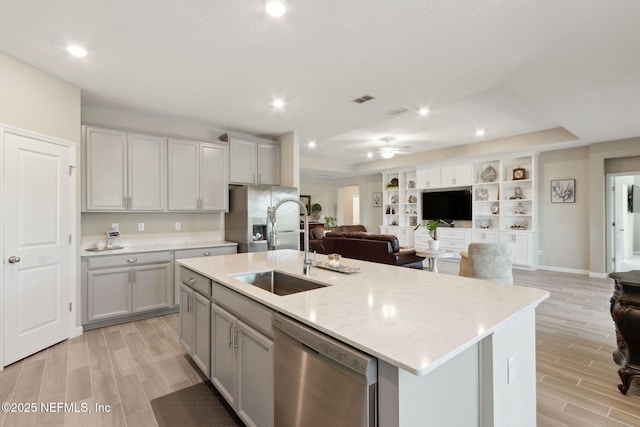 kitchen with gray cabinets, stainless steel appliances, a sink, and open floor plan