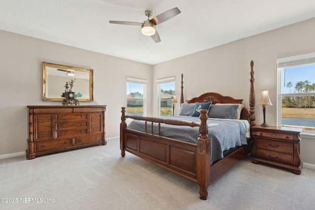 bedroom featuring light carpet, multiple windows, a ceiling fan, and baseboards