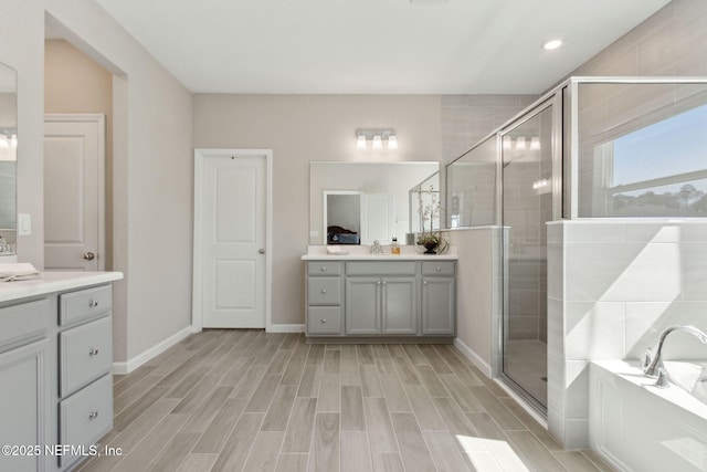 full bathroom featuring wood finish floors, two vanities, a shower stall, and a bath