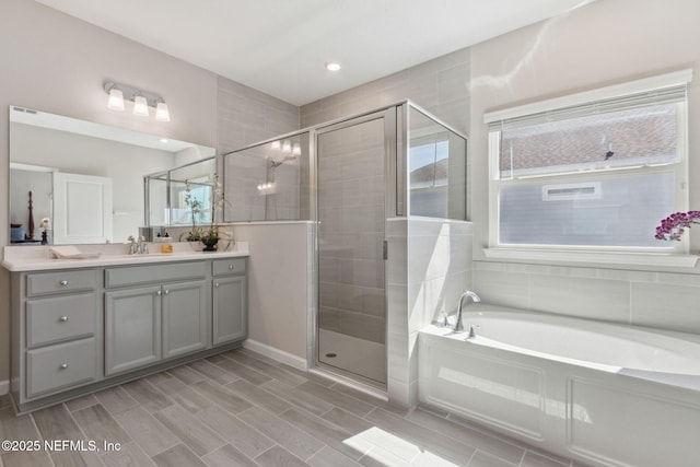 bathroom with a shower stall, vanity, and a bath