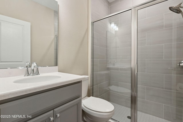 bathroom featuring toilet, a stall shower, and vanity