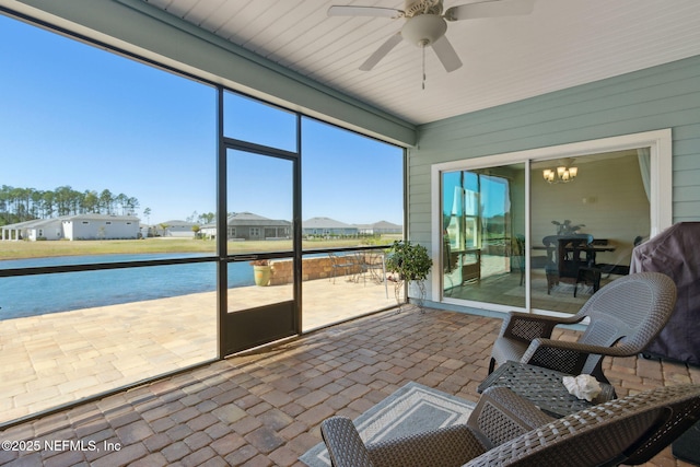 sunroom with ceiling fan with notable chandelier and a water view