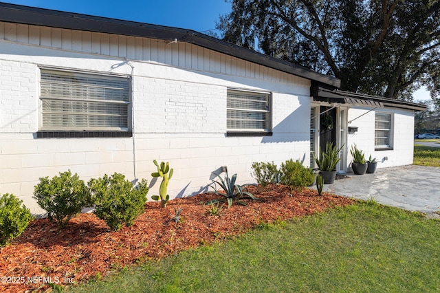 view of front facade featuring a front yard, concrete block siding, and a patio