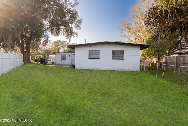 rear view of house with a fenced backyard and a yard