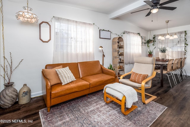 living area with ceiling fan with notable chandelier, wood finished floors, beam ceiling, and baseboards