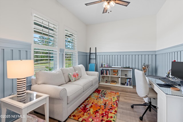 office space with a wainscoted wall, wood finished floors, and a ceiling fan