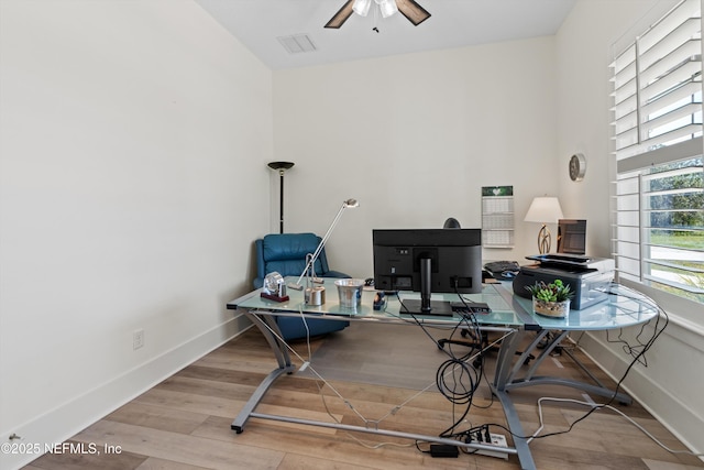 office area with ceiling fan, a high ceiling, wood finished floors, visible vents, and baseboards