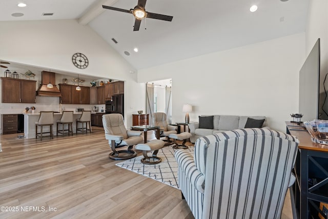 living room with visible vents, ceiling fan, light wood-type flooring, high vaulted ceiling, and beam ceiling