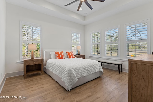 bedroom with ceiling fan, recessed lighting, baseboards, light wood-style floors, and a tray ceiling