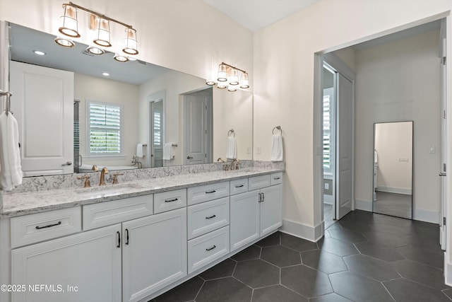 bathroom featuring baseboards, double vanity, a sink, and tile patterned floors