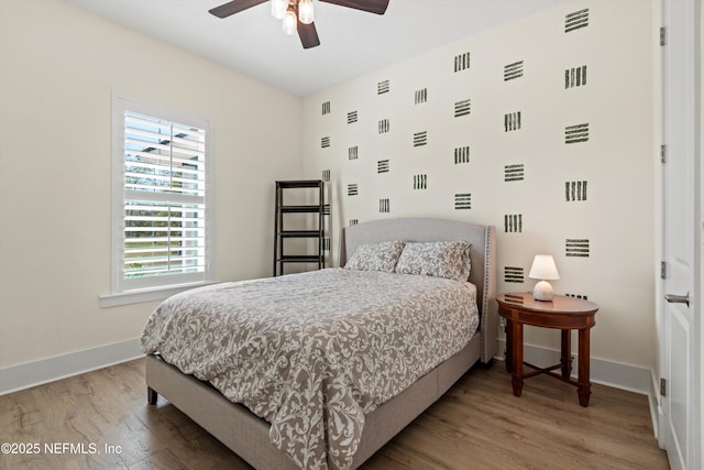 bedroom with a ceiling fan, baseboards, and wood finished floors