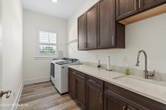 laundry room with separate washer and dryer, a sink, baseboards, cabinet space, and light wood finished floors