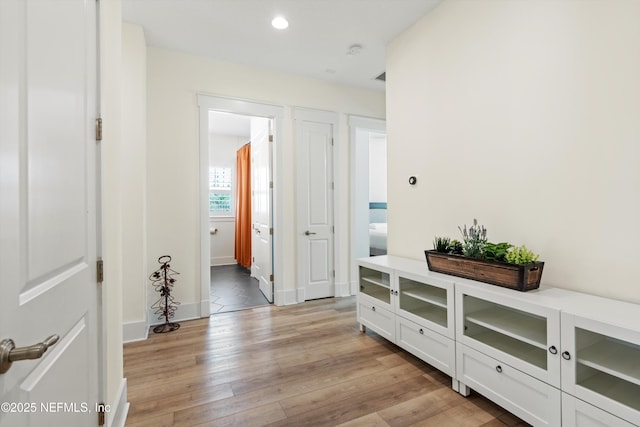 corridor with light wood-type flooring, baseboards, and recessed lighting