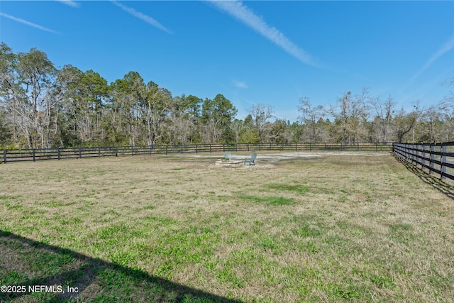 view of yard with fence and a rural view