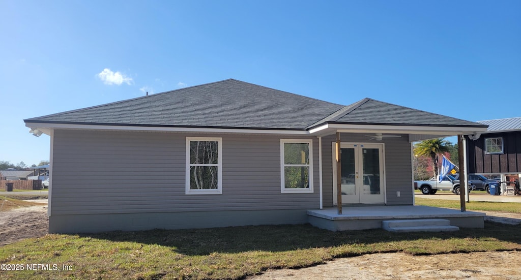 rear view of house featuring french doors, roof with shingles, and a lawn