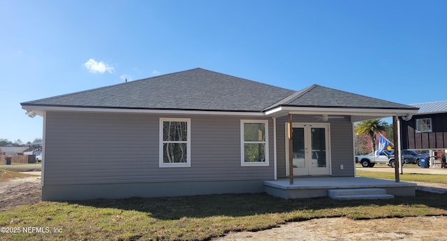 back of house with french doors, a yard, and a shingled roof