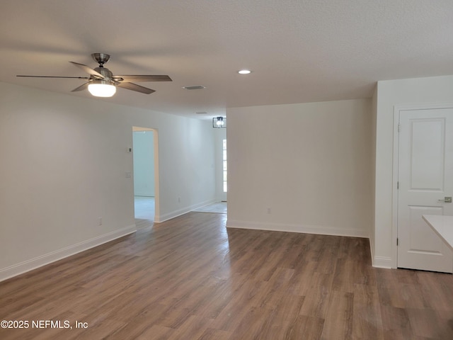 unfurnished room with visible vents, baseboards, wood finished floors, a textured ceiling, and a ceiling fan
