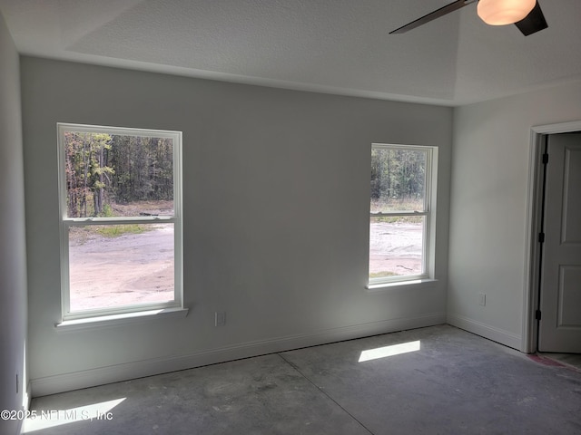 spare room with a ceiling fan, baseboards, concrete floors, and a textured ceiling