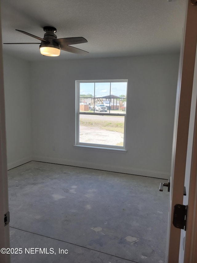 spare room featuring baseboards, a textured ceiling, unfinished concrete flooring, and a ceiling fan