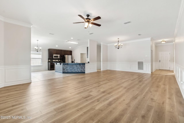 unfurnished living room with light wood-style flooring, ceiling fan with notable chandelier, a sink, visible vents, and ornamental molding