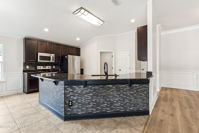 kitchen with dark brown cabinetry, a breakfast bar area, stainless steel appliances, and crown molding