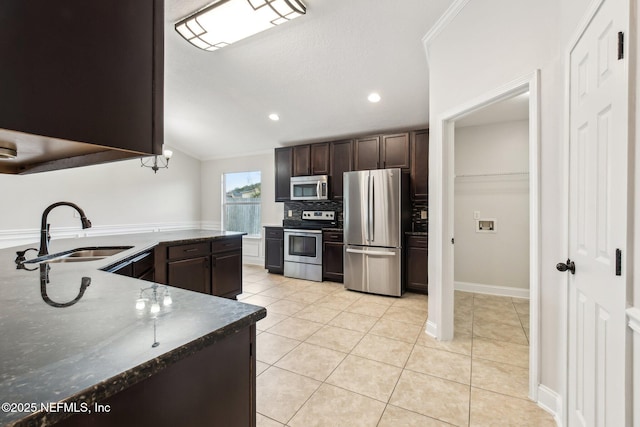 kitchen with dark brown cabinetry, appliances with stainless steel finishes, a sink, and light tile patterned flooring