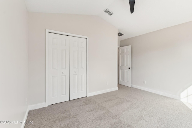 unfurnished bedroom with baseboards, visible vents, carpet, vaulted ceiling, and a closet