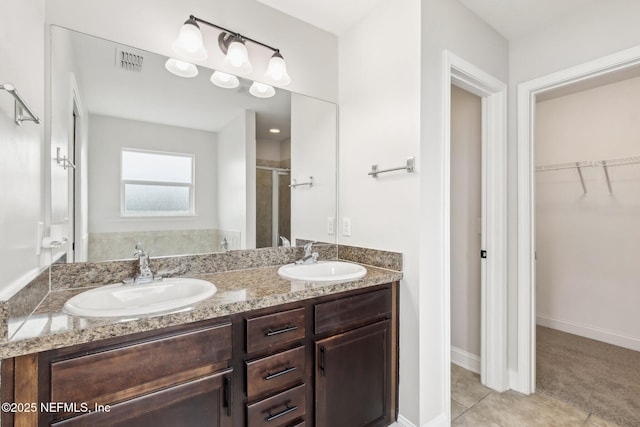 bathroom featuring a walk in closet, a sink, visible vents, and a shower stall