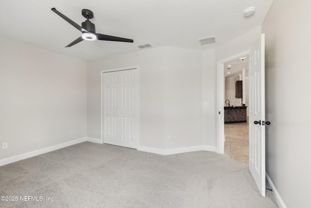 unfurnished bedroom featuring a closet, visible vents, light carpet, and baseboards