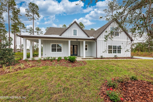 modern farmhouse style home featuring metal roof, roof with shingles, a standing seam roof, a front lawn, and board and batten siding