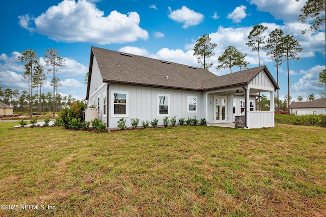 rear view of property with board and batten siding, a shingled roof, a lawn, and french doors