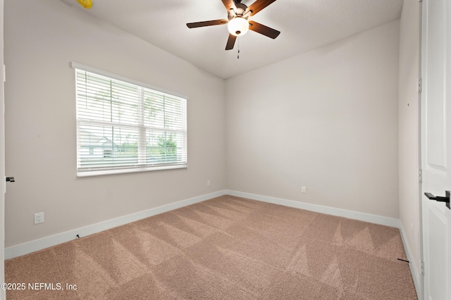 carpeted spare room featuring ceiling fan and baseboards