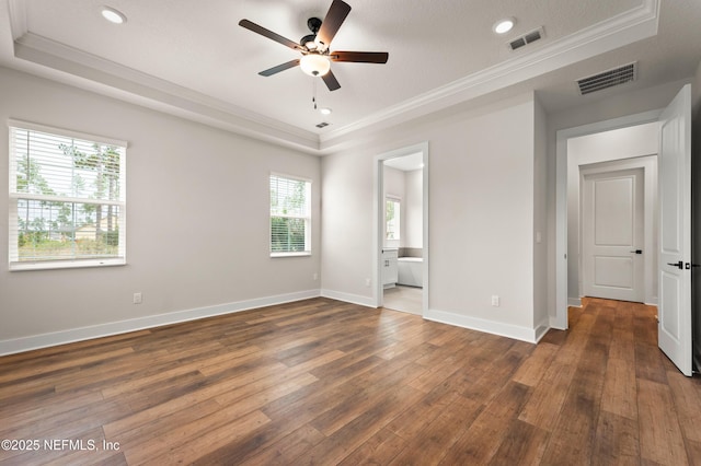 unfurnished bedroom featuring hardwood / wood-style floors, a tray ceiling, and visible vents