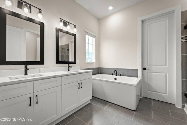 full bath with tile patterned flooring, a freestanding tub, a sink, and double vanity