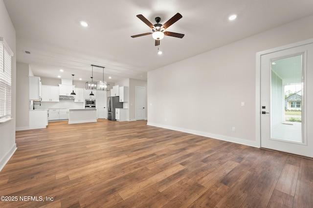 unfurnished living room with baseboards, a ceiling fan, wood finished floors, and recessed lighting