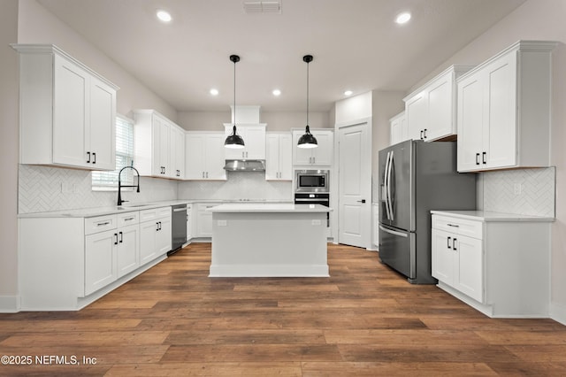 kitchen with stainless steel appliances, dark wood-style flooring, a sink, and under cabinet range hood