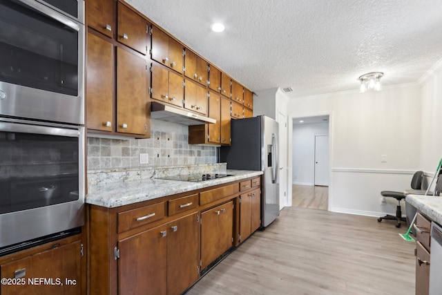 kitchen with ornamental molding, decorative backsplash, light countertops, stainless steel appliances, and under cabinet range hood