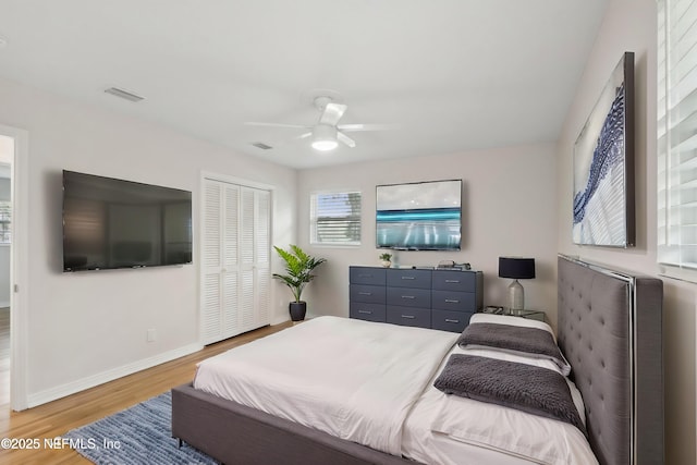 bedroom featuring visible vents, wood finished floors, a closet, baseboards, and ceiling fan