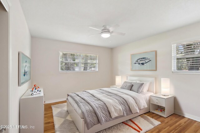bedroom with baseboards, light wood-style floors, and a ceiling fan