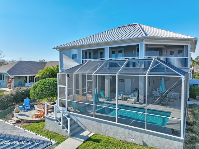 rear view of property featuring metal roof, a lanai, an outdoor pool, a standing seam roof, and a patio area